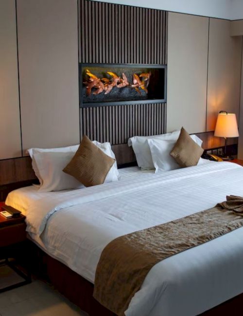 This image shows a neatly made hotel room bed with two bedside tables, lamps, and decorative pillows, creating a cozy and inviting atmosphere.