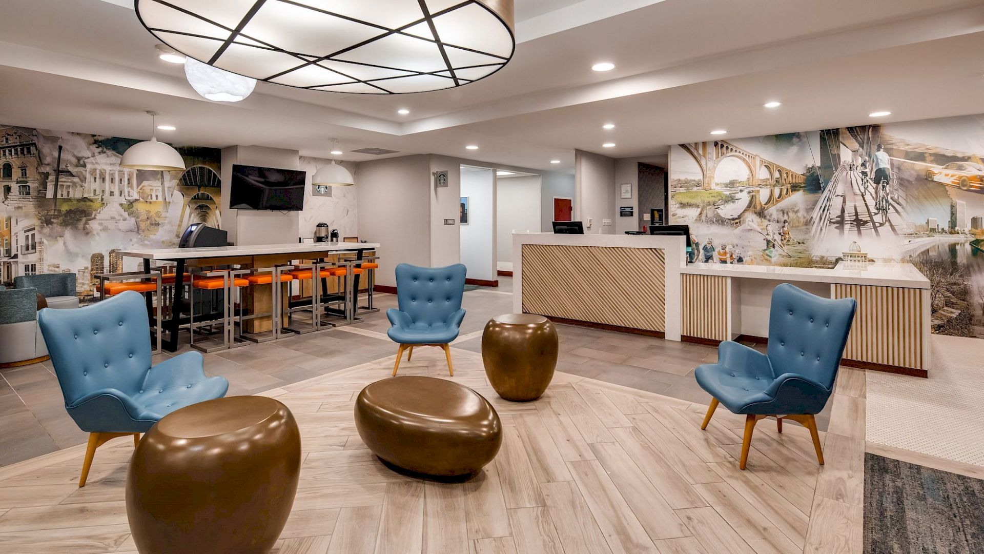 A modern lobby with blue chairs, brown ottomans, a front desk, wall art, bar seating, and contemporary lighting fixtures ends the sentence.