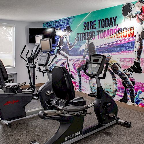 A gym with exercise equipment and a vibrant mural saying 